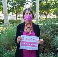 image of a woman wearing pink and black, holding a sign