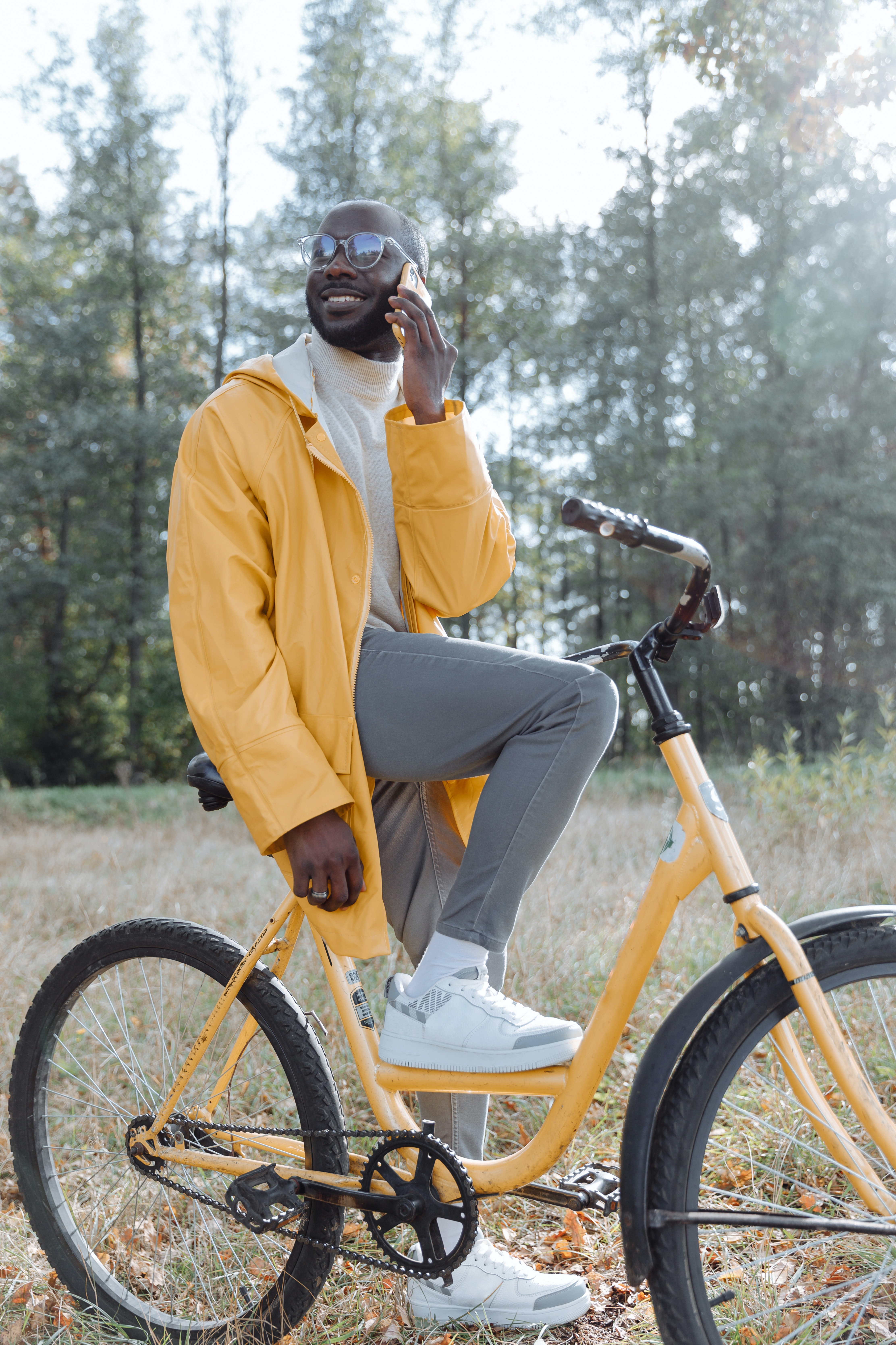 stylish man holding phone to ear while stopped on a trendy yellow bycycle