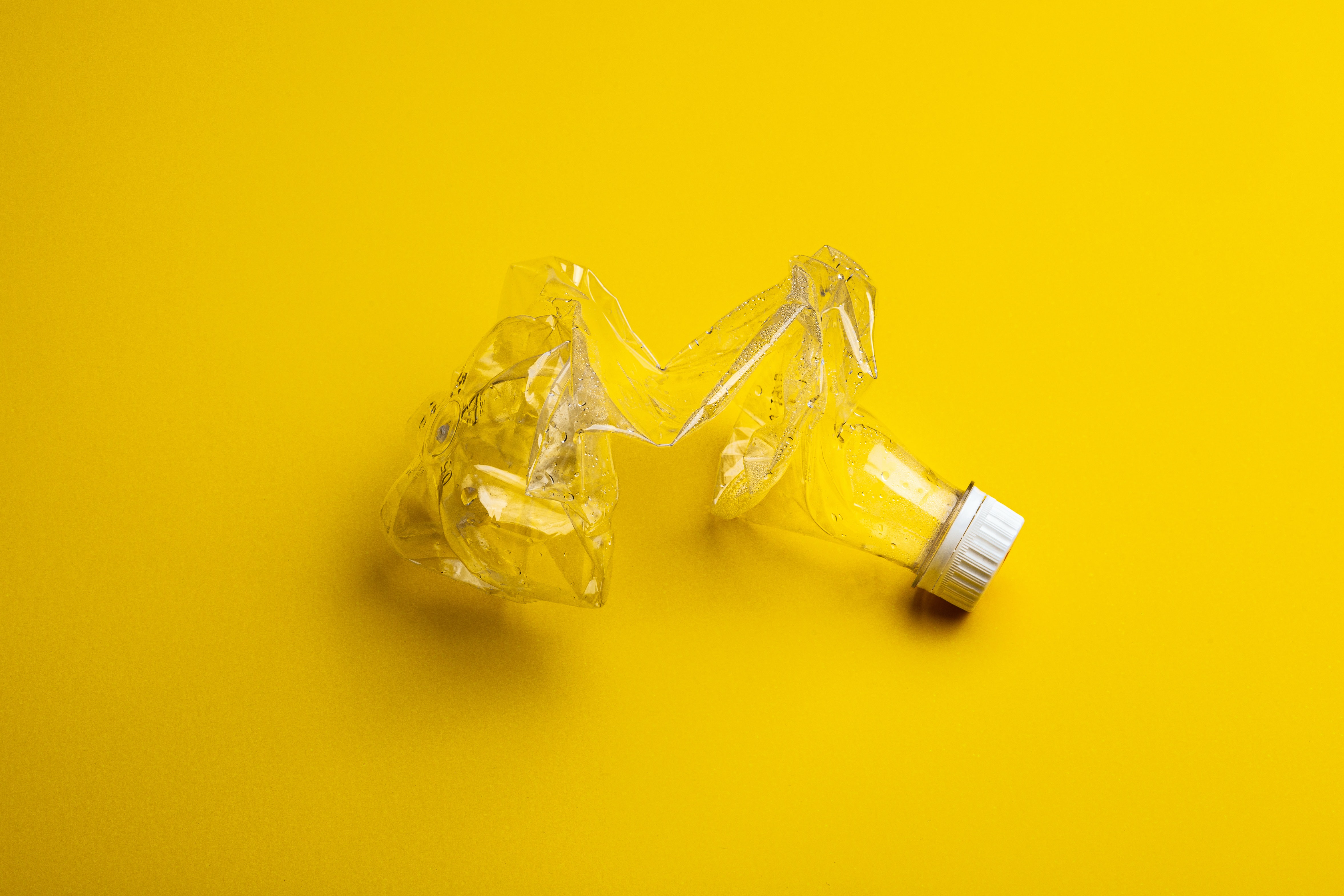 Crushed plastic bottle on yellow background
